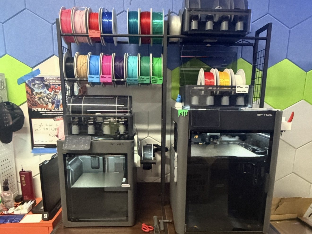 A fabrication workbench with 3D printers and filament spools.
